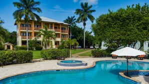 Un hotel con piscina, palmeras y un jardín bien cuidado.