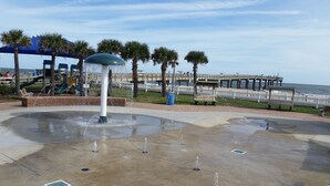 A water feature with a central fountain, benches, palm trees, and a boardwalk by the beach. - 2/2 Condo, Ground Floor, 2 Parking Spaces, Pool (Saint Augustine Beach)