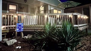 A two-story house with a porch, a mailbox, and a large umbrella.