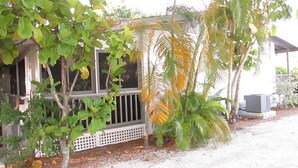 A house with a porch, surrounded by various trees and plants.