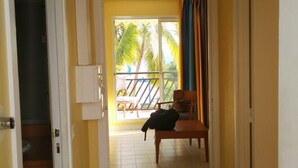 A hallway with a view to a balcony, a chair, and a coat on the floor. - Marco Polo (Saint-François)