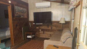 A cozy living room with a television, sofa, and a small table.