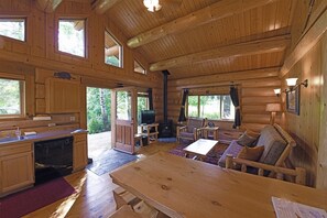 Ein Holzblockhaus-Interieur mit Küche, Essbereich und Wohnzimmer.