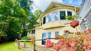 Une maison à deux étages, dotée d’un toit incurvé, de grandes fenêtres et d’une terrasse en bois.