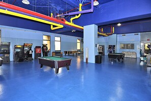 A recreational area with pool tables, arcade games, and a blue floor. - XPLORIE ACTIVITIES & LINENS INCLUDED*! Capri 2BR/2BA Condo with Ocean & Bay Views! Sunday-Sunday reservations. (Ocean City)
