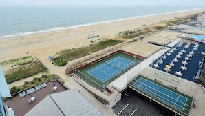 Vista a la playa, cancha de tenis y zona de piscina.