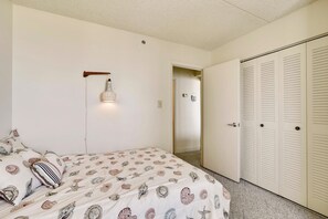 A bedroom with a bed, a hanging light fixture, a closet with louvered doors, and a door leading to another room. - XPLORIE ACTIVITIES & LINENS INCLUDED*! Capri 2BR/2BA Condo with Ocean & Bay Views! Sunday-Sunday reservations. (Ocean City)