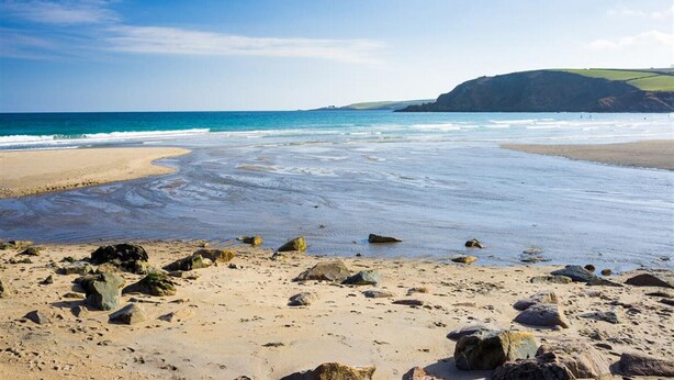 A beach with a rocky foreground, a sandy shore, and a view of the ocean and cliffs in the distance. - Tinners Forge - One Bedroom Cottage, Sleeps 2 (Polgooth)
