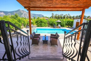 A covered outdoor area with a pool, wicker furniture, and a view of mountains. - Pomegranate Garden Villas. Three villas, 12 - 21 guests. Two swimming pools.
(Dalyan)