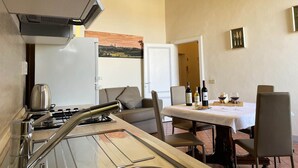 Eine kompakte Küche mit Gasherd, einem weißen Kühlschrank und einem Essbereich mit Tisch für zwei Personen.