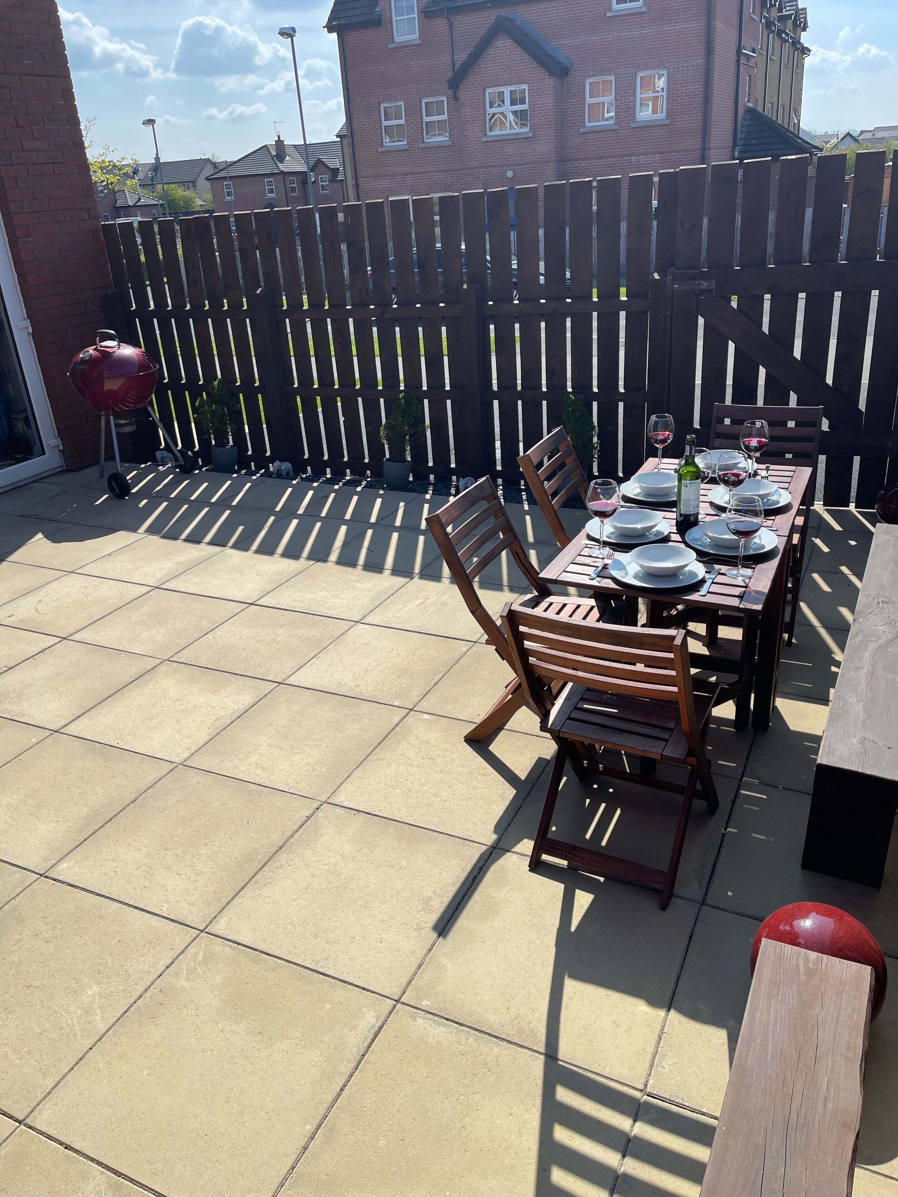 Une terrasse avec une table dressée pour les repas, des chaises et un barbecue.