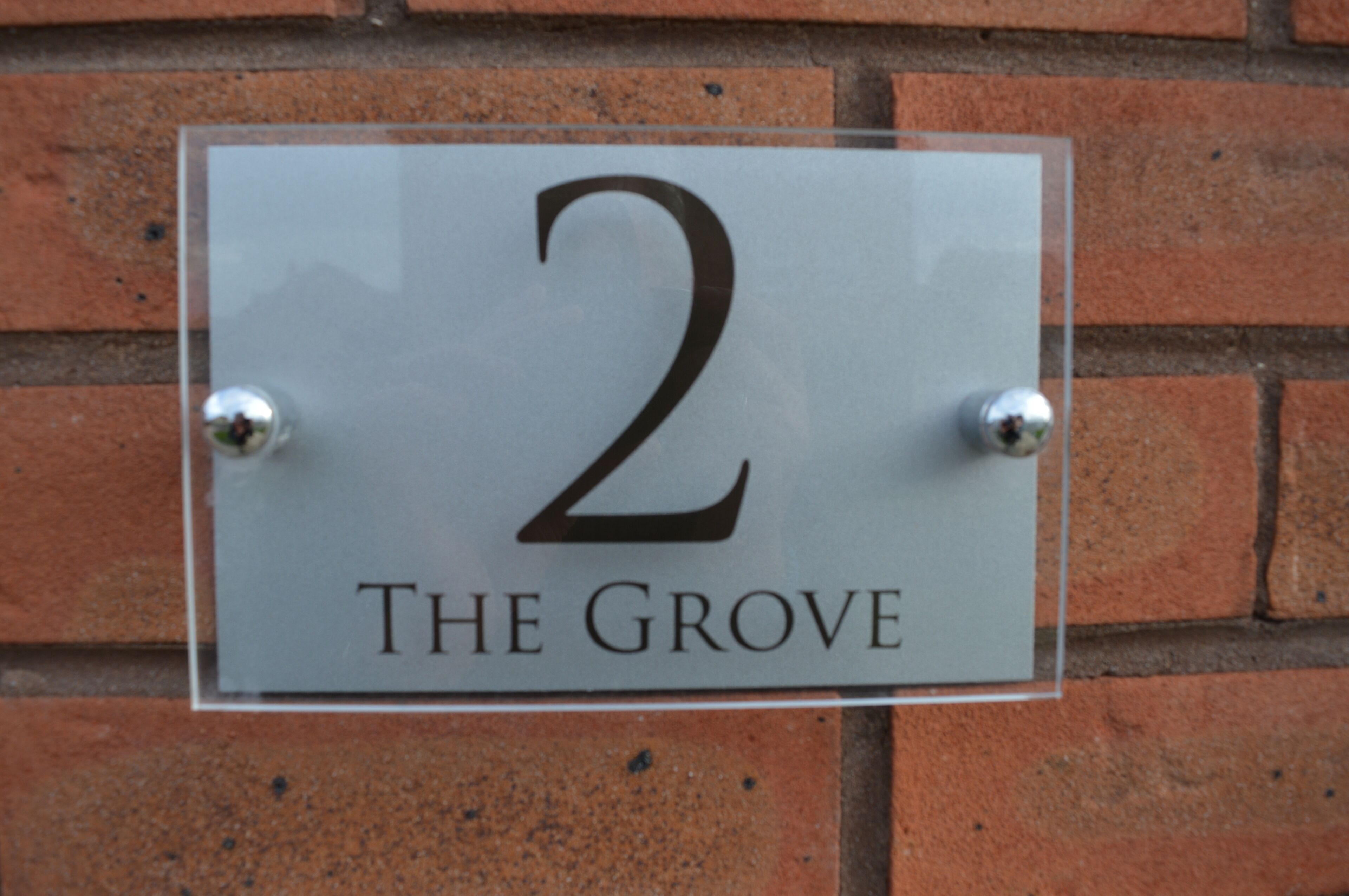 A sign with the number 2 and the text "The Grove" mounted on a brick wall.