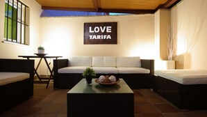 Ein gemütlicher Wohnbereich mit einer Couch, zwei Sesseln, einem Couchtisch mit Dekoration und einem Schild mit der Aufschrift 'LOVE TARIFA'.