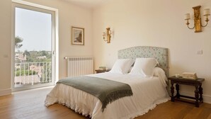 Een slaapkamer met een groot bed, een balkon en uitzicht over de stad.