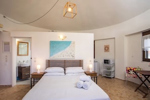 A hotel room with a bed, bedside lamps, a painting, a microwave, a chair, and a small table.