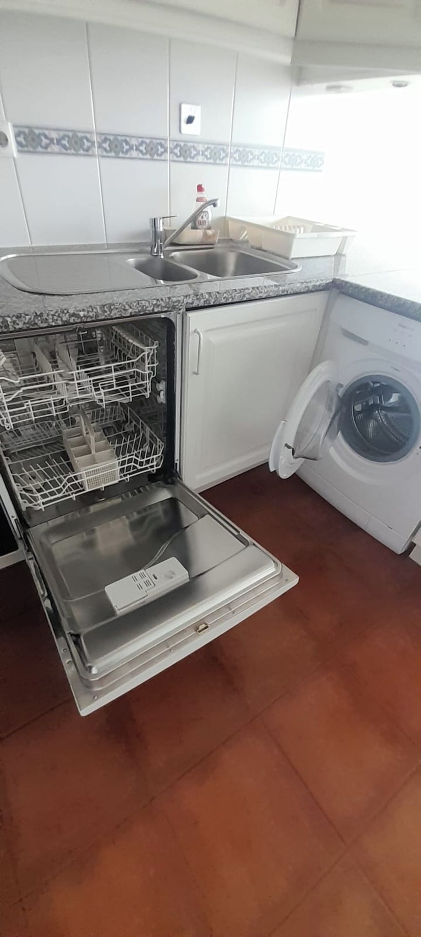 Una cucina con lavastoviglie, lavatrice e rivestimento a mosaico.