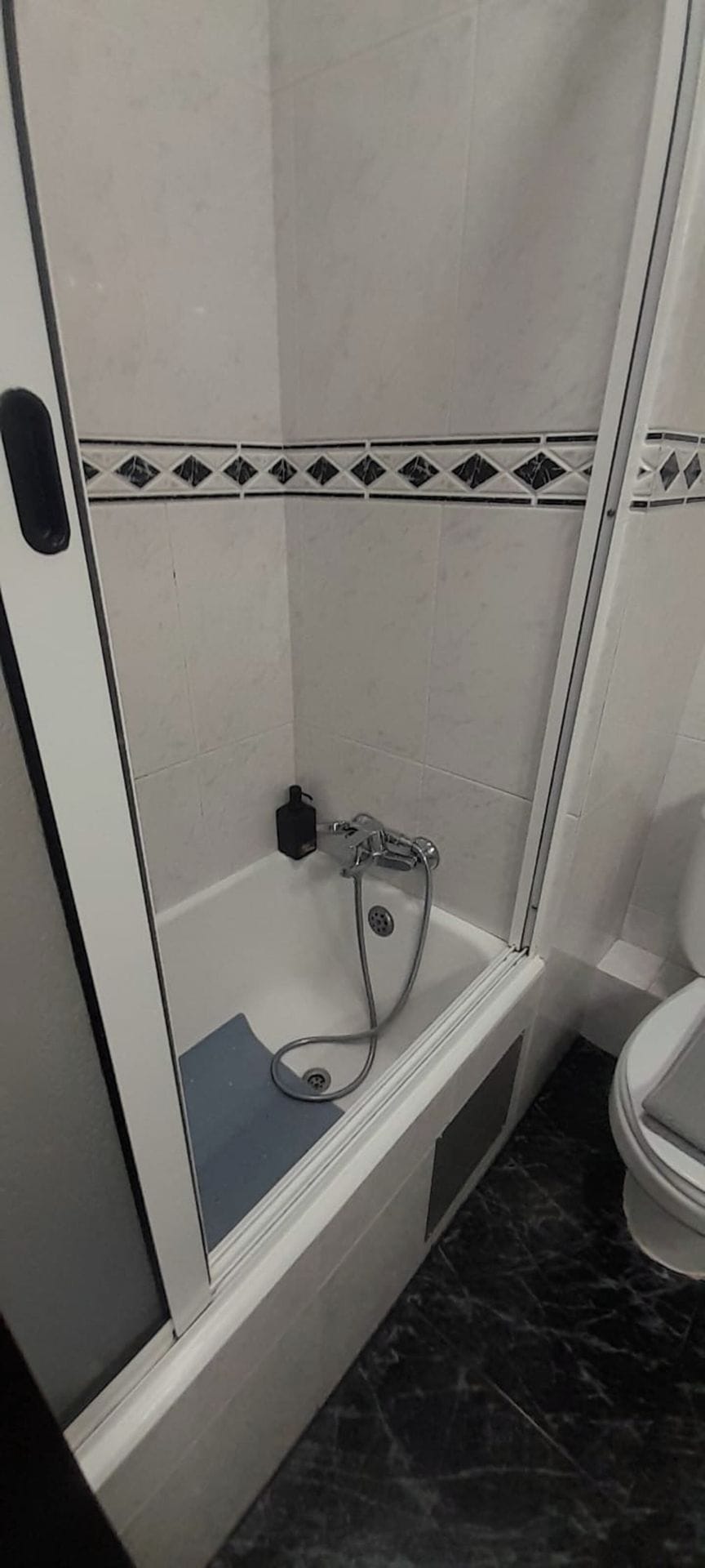 A bathroom with a shower enclosure, a toilet, and a sink.