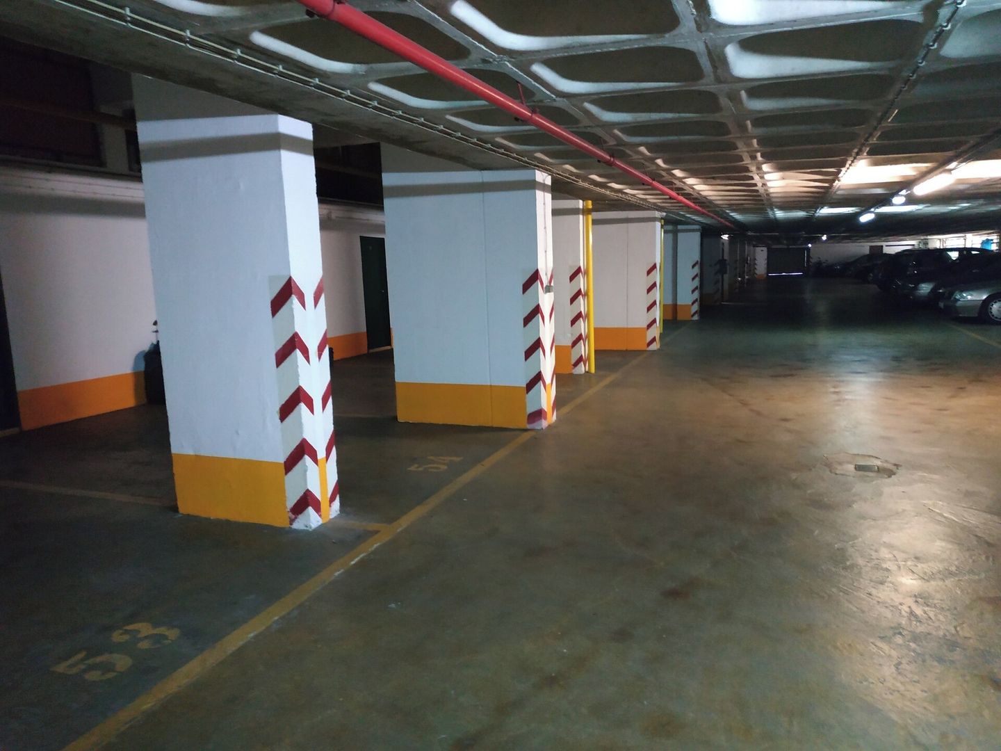 Ett parkeringshus i flera våningar med betongpelare och gula linjer på golvet.