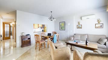 Ein großzügiges Wohnzimmer mit einer Couch, Sesseln und einem Essbereich mit Tisch und Stühlen.
