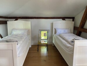 Una habitación con dos camas, una mesita y una ventana.