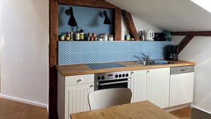 Una cucina compatta con un piano di lavoro in legno, un forno integrato e un armadietto bianco.