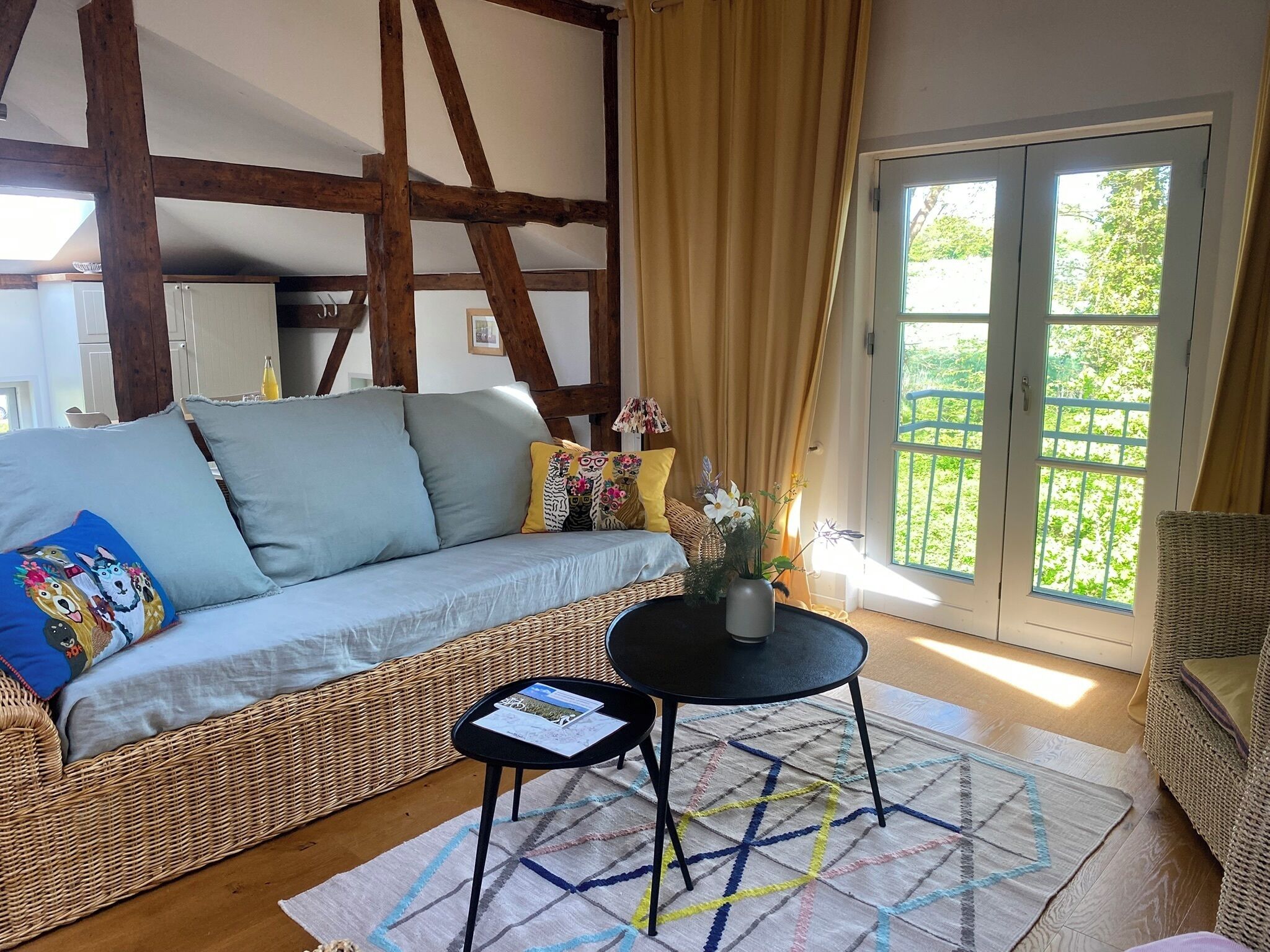 Una sala de estar acogedora con un sofá, una mesita y vistas de un jardín a través de una puerta corrediza.