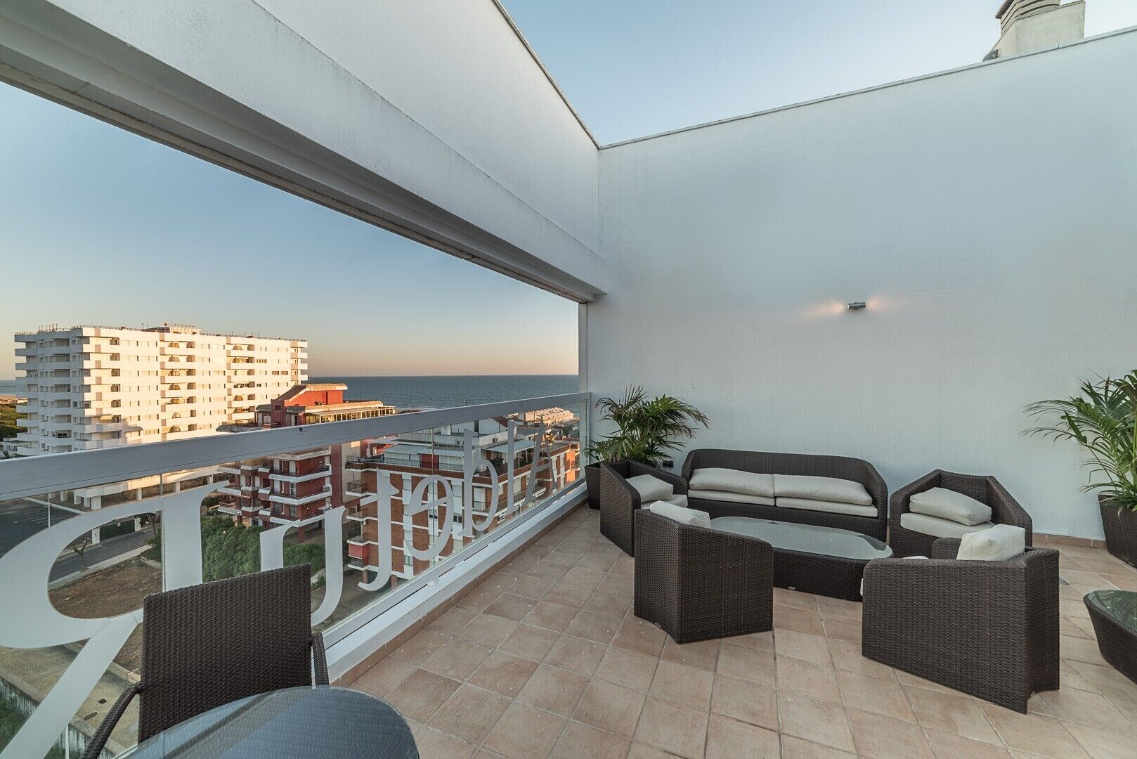 Ein Balkon mit Gartenmöbeln, Blick auf das Meer und ein Gebäude im Hintergrund.