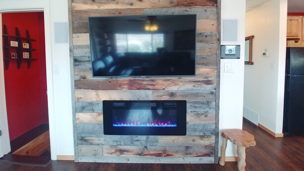 Una sala de estar moderna con un panel de pared de madera, un televisor de pantalla plana y una chimenea debajo.