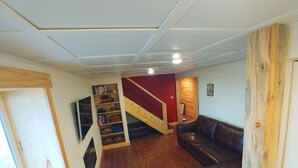 Un espacio habitable amplio con una escalera de madera, un sofá de cuero y una estantería empotrada.