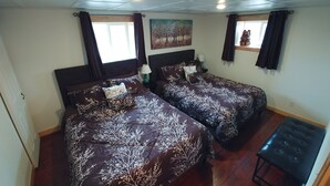Habitación de hotel con dos camas, un banco, un cuadro y una ventana con cortinas.