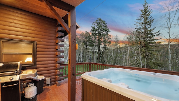 A wooden deck with a hot tub, grill, and propane tank. - Circle J Lodge, Relaxing pet friendly cabin at Terry Peak with new hot tub! (Lead)