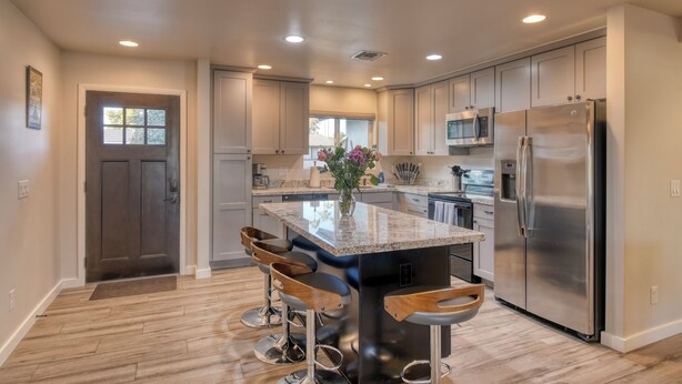 A modern kitchen with a central island, stainless steel appliances, and wooden bar stools. - Downtown Gilbert Getaway - Sleeps 8 (Gilbert)
