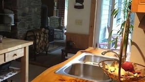 Una cocina con encimera de madera, pared de piedra y vistas al exterior.
