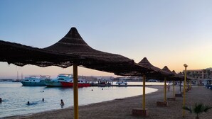 Ein Strand mit Strohdächern und einem Sandufer.