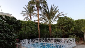 Ein Poolbereich mit zwei Liegestühlen, einem weißen Poolzaun und Palmen.