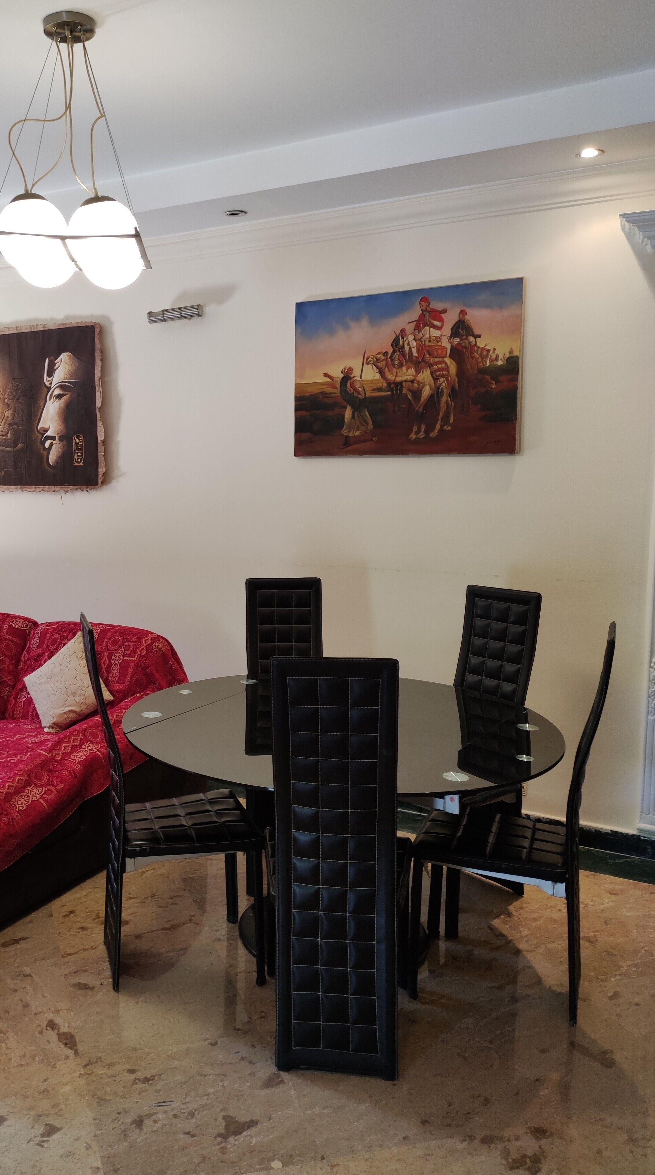 Un comedor con una mesa redonda, sillas negras y un sofá rojo.