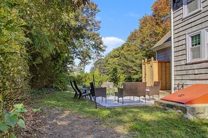 Une terrasse avec des meubles d’extérieur, une clôture en bois et une maison dont on peut voir la porte et les fenêtres.
