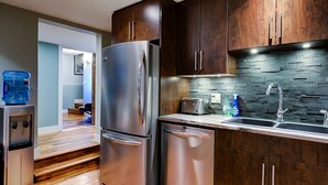 A modern kitchen with stainless steel appliances, dark wooden cabinets, and a stone backsplash. - 5-star Okanagan Getaway Pet Friendly, Privacy (Lake Country)