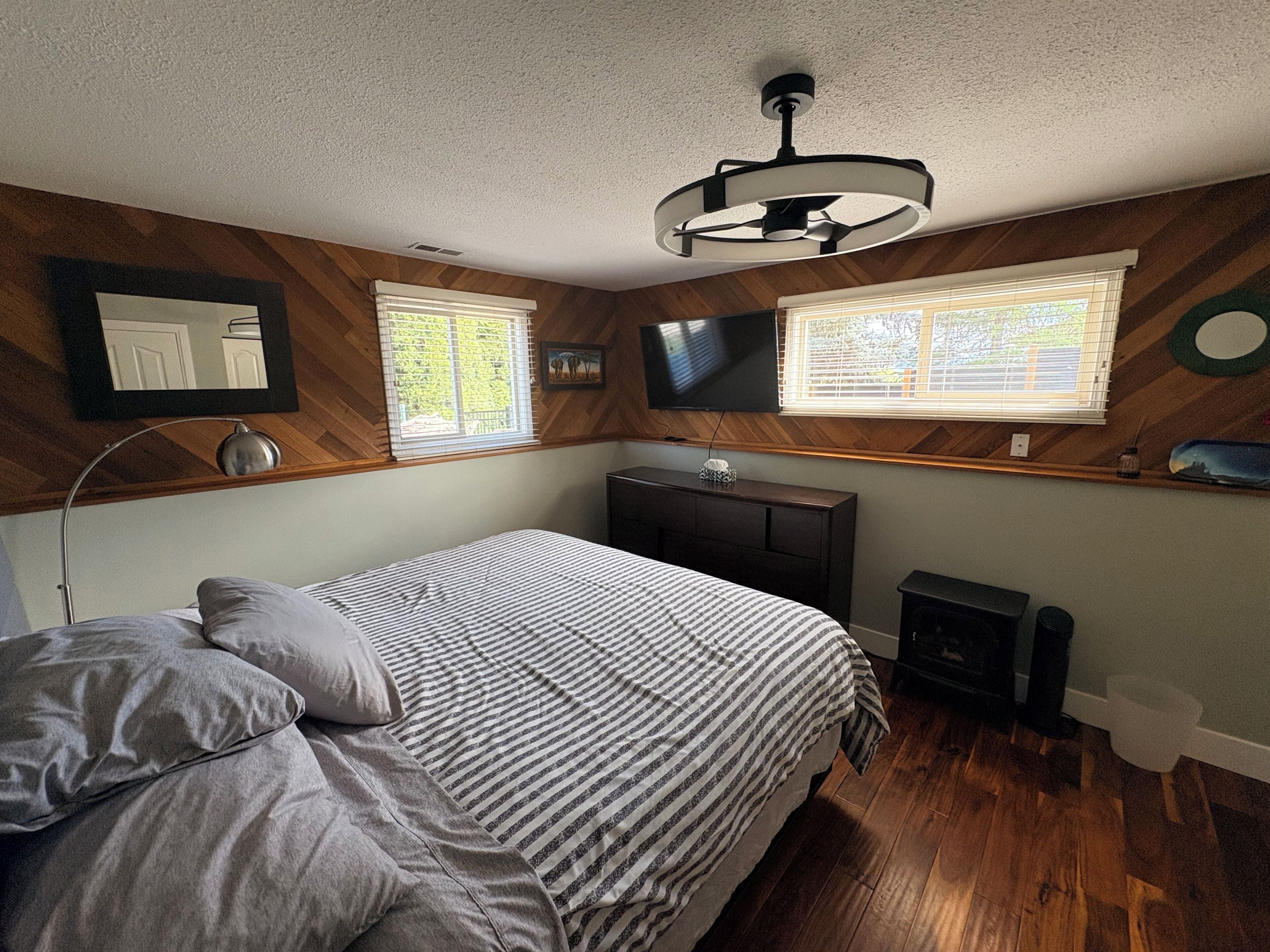 Une chambre à coucher avec un lit, une télévision, un bureau et une fenêtre avec des stores.