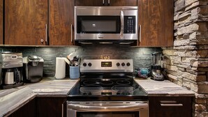 A modern kitchen with stainless steel appliances, a stone accent wall, and wooden cabinets. - 5-star Okanagan Getaway Pet Friendly, Privacy (Lake Country)