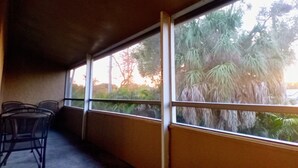 Zona d'estar a l'aire lliure coberta amb vistes a arbres i un edifici.