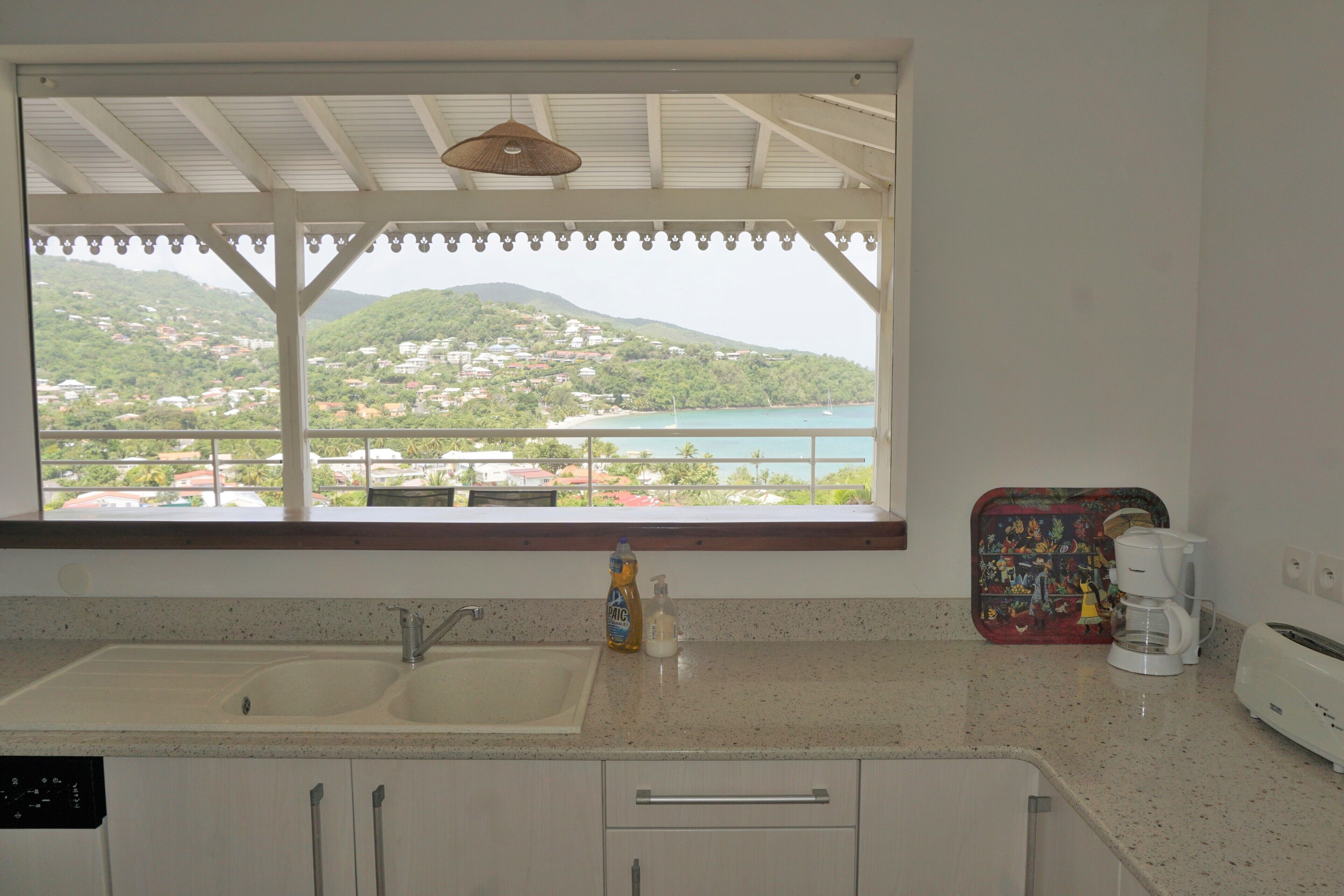 A kitchen with a large window, a sink, a coffee maker, and a toaster.
