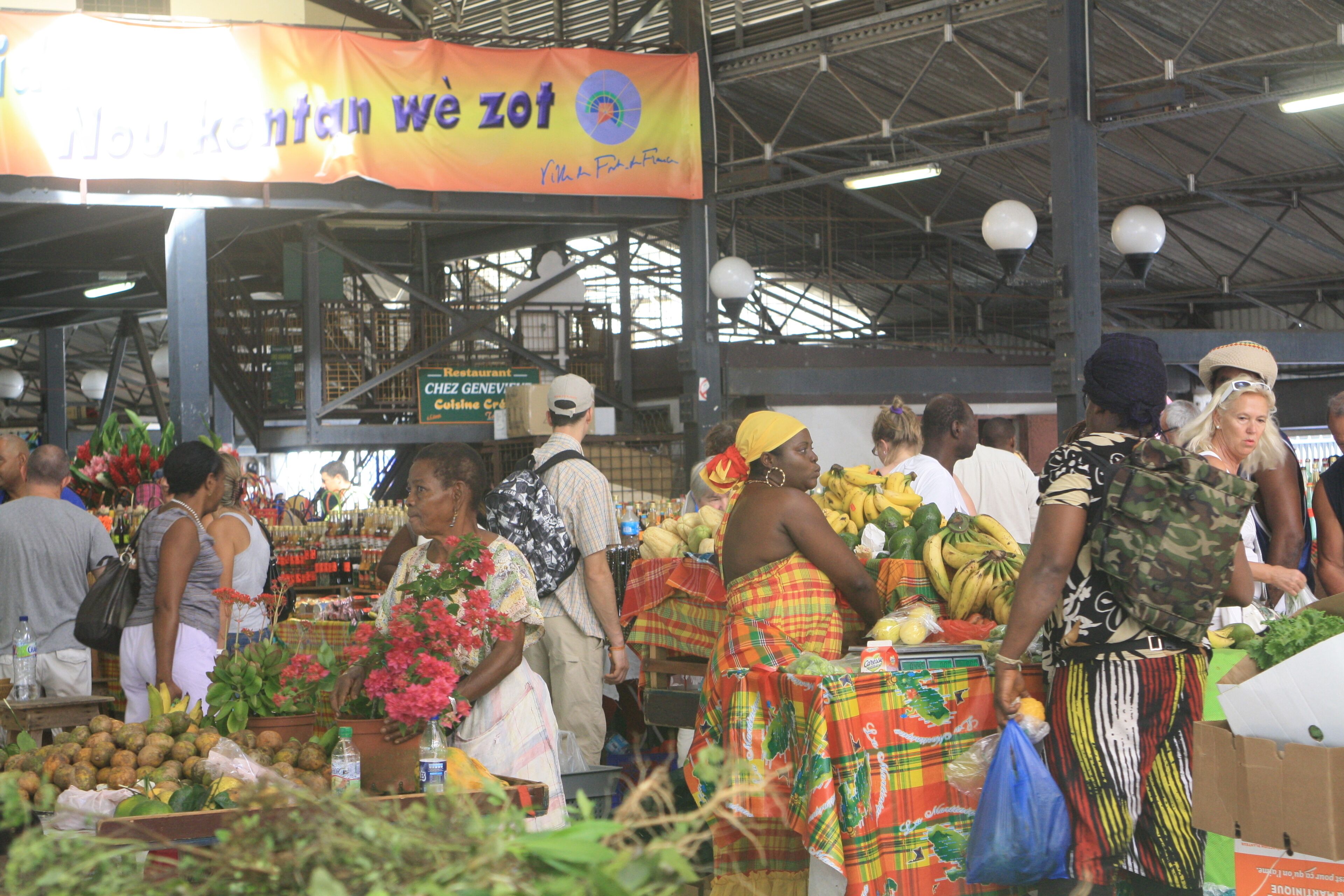 An indoor market with various stalls selling fruits and vegetables.