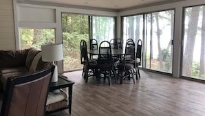 Een ruime kamer met een grote eettafel, omringd door stoelen, een bank en een lamp.