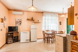 Cocina compacta con refrigerador, enfriador de vinos y comedor con mesa y sillas.