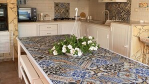A kitchen with a tiled island, white cabinets, and a hanging plant. - Red-house near the beach and with  (Avola-Siracusa)