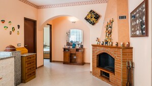A living room with a fireplace, wooden cabinet, and decorative wall art. - Red-house near the beach and with  (Avola-Siracusa)