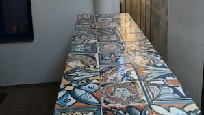 Un pasillo estrecho con un banco de azulejos y una reja de metal.