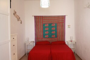 A bedroom with a double bed, two bedside tables, a hanging tapestry, and a white wardrobe. - Stromboli, At Nino's House (Stromboli)