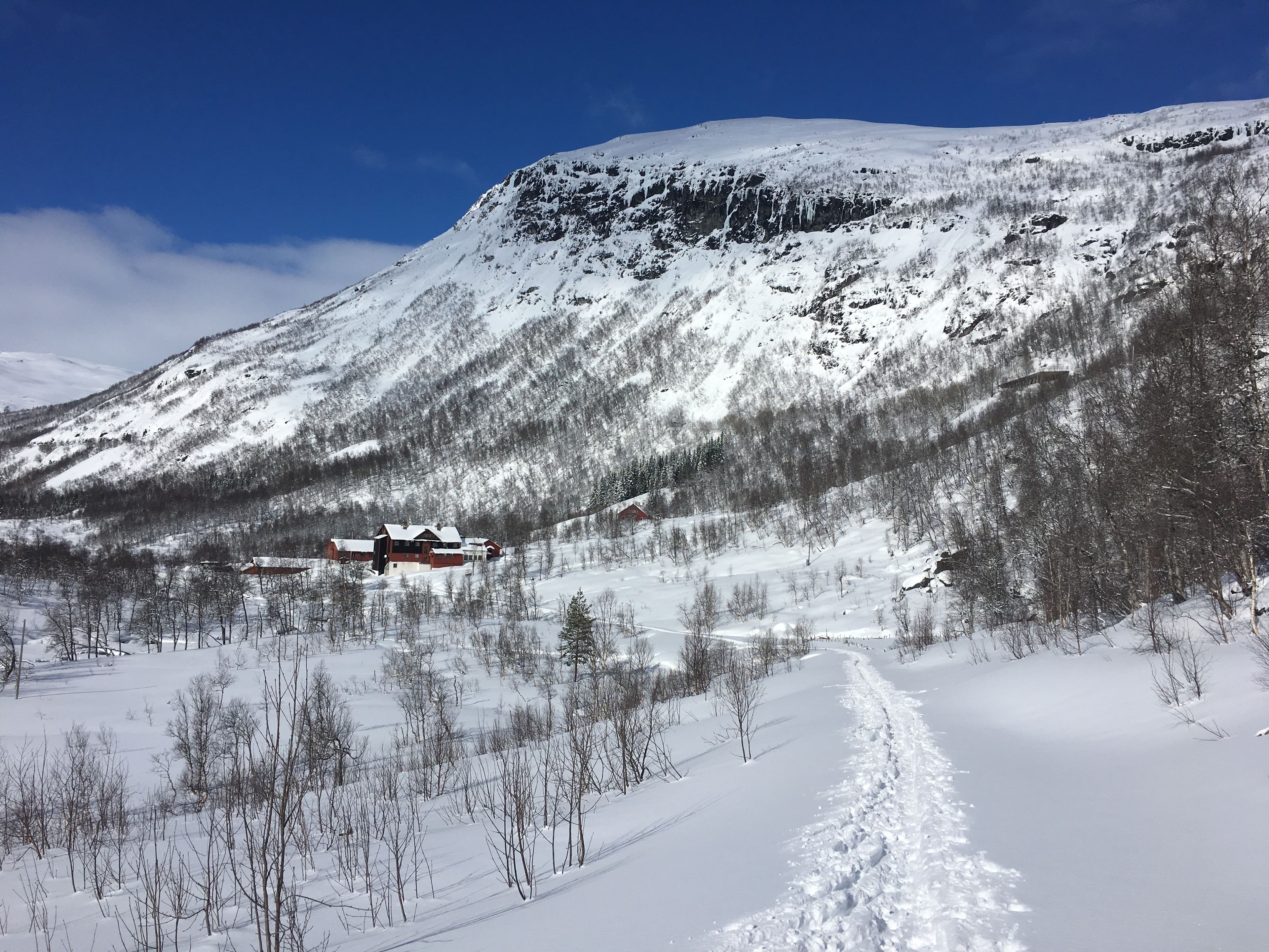 Une montagne enneigée, avec un chalet et un ciel dégagé.